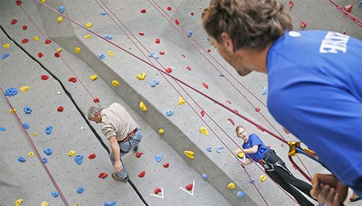 体育菠菜大平台 student climbing the rock wall at the wellness center